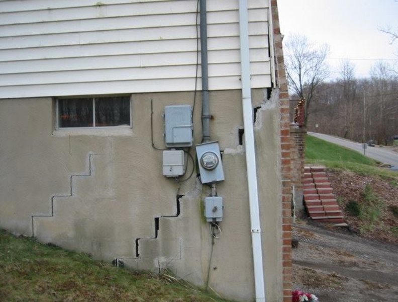 Photo of house exterior showing the foundation bricks separating and causing the electric meter to bend | DRY BASEMENT®