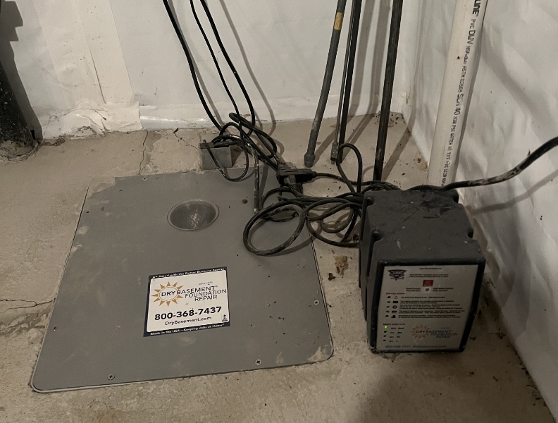 Photo of sump pump and basin in a basement with a sticker for Dry Basement Foundation Repair