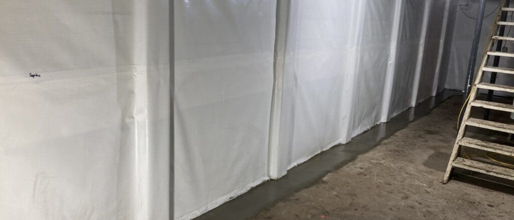 Photo of a basement wall lined with white insulation to prevent flooding.