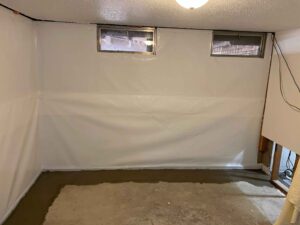 Interior waterproofing system installed along basement wall with new concrete sealing the drainage trench